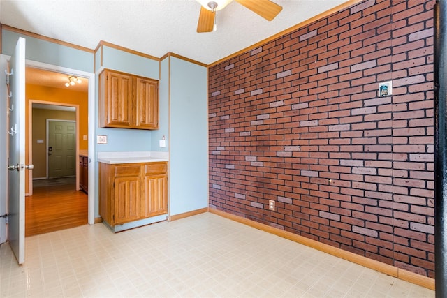 kitchen with crown molding, brick wall, and a textured ceiling