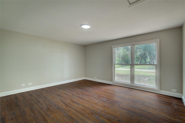 unfurnished room featuring baseboards and dark wood-style flooring