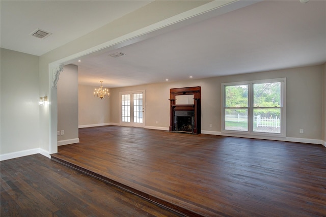 unfurnished living room with dark wood finished floors, an inviting chandelier, a fireplace, and baseboards