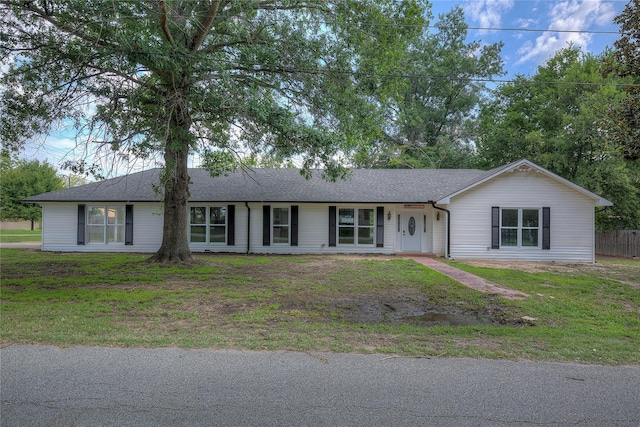 single story home featuring a front lawn and roof with shingles