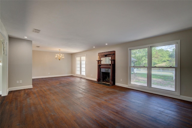 unfurnished living room with plenty of natural light, dark wood-type flooring, and an inviting chandelier