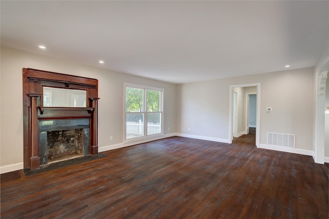 unfurnished living room featuring visible vents, baseboards, dark wood-type flooring, and a fireplace with flush hearth