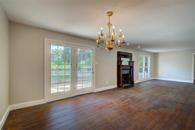 unfurnished living room featuring a high end fireplace, dark hardwood / wood-style flooring, and an inviting chandelier