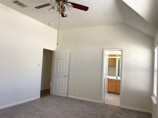 empty room featuring a textured ceiling, ceiling fan, vaulted ceiling, and carpet floors