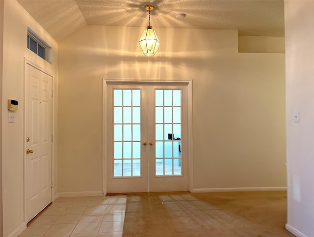 entryway with lofted ceiling, french doors, light tile patterned flooring, and a wealth of natural light