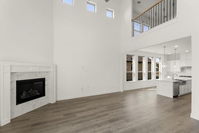 unfurnished living room with a towering ceiling, dark wood-type flooring, and a high end fireplace