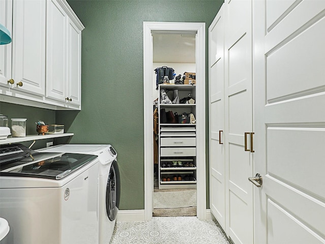 laundry area with washer and dryer, light tile patterned floors, and cabinets