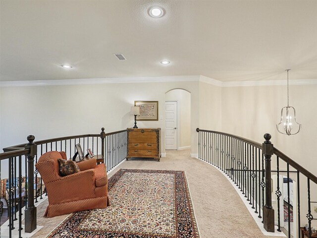 corridor with ornamental molding, light colored carpet, and a notable chandelier