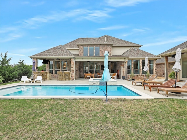 view of swimming pool with an outdoor kitchen, a yard, exterior bar, and a patio