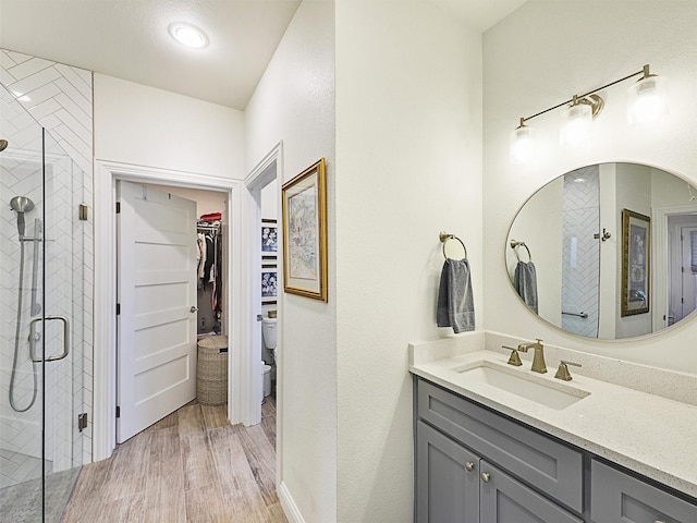 bathroom with an enclosed shower, vanity, toilet, and wood-type flooring