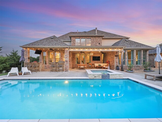 view of pool featuring an in ground hot tub, an outdoor bar, ceiling fan, and a patio area