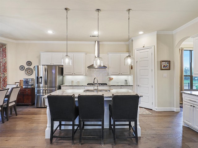 kitchen featuring stainless steel refrigerator with ice dispenser, white cabinetry, and an island with sink