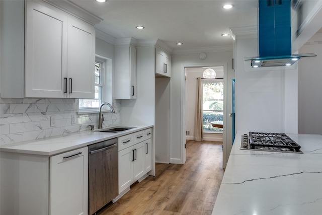 kitchen with sink, stainless steel appliances, wall chimney range hood, light stone counters, and white cabinets