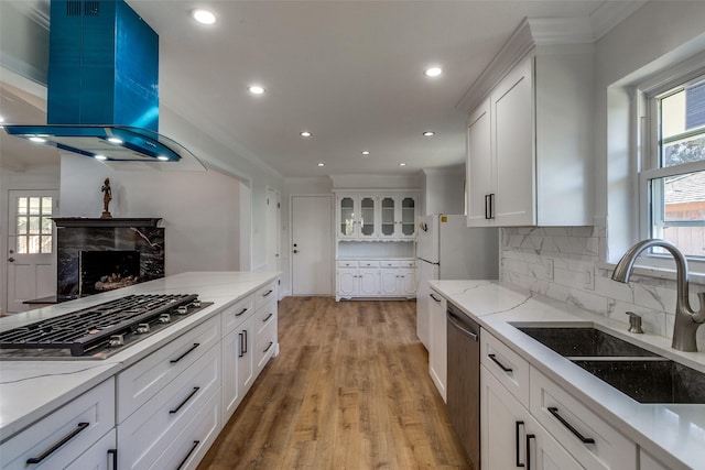 kitchen featuring light wood-type flooring, ventilation hood, stainless steel appliances, sink, and white cabinets