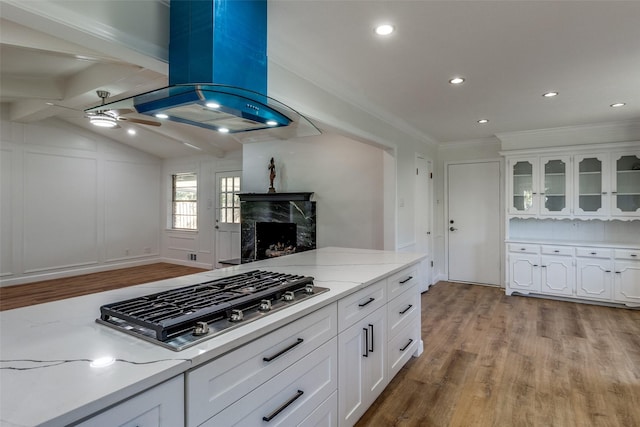 kitchen with vaulted ceiling with beams, white cabinetry, stainless steel gas cooktop, and light hardwood / wood-style flooring