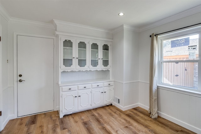 unfurnished dining area featuring ornamental molding and light wood-type flooring