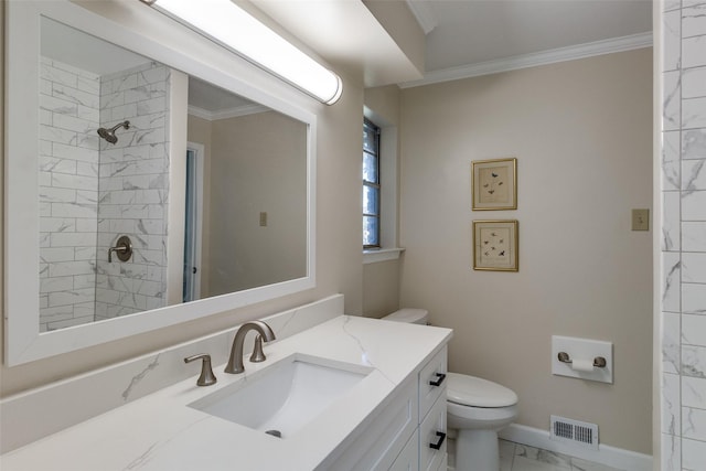 bathroom with a tile shower, vanity, toilet, and crown molding