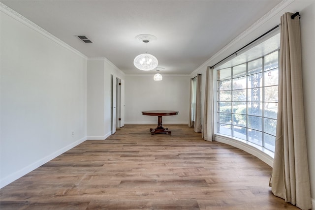 unfurnished dining area with light wood-type flooring, ornamental molding, and a notable chandelier