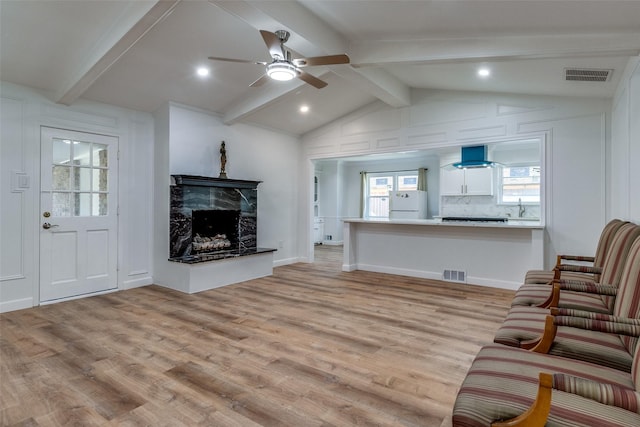 living room featuring ceiling fan, sink, a fireplace, and light hardwood / wood-style flooring