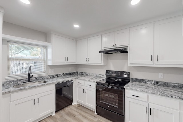 kitchen with under cabinet range hood, a sink, light wood-style floors, white cabinets, and black appliances