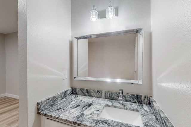 bathroom featuring a textured wall, wood finished floors, vanity, and baseboards