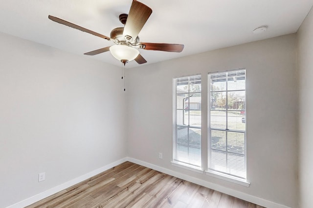 empty room featuring light wood finished floors, a ceiling fan, and baseboards