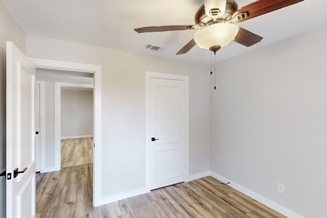 unfurnished bedroom with light wood finished floors, a ceiling fan, visible vents, and baseboards