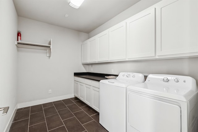 laundry room with dark tile patterned flooring, washer and clothes dryer, cabinet space, and baseboards