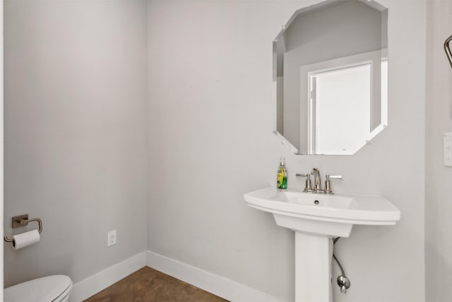 bathroom featuring toilet, baseboards, and a sink