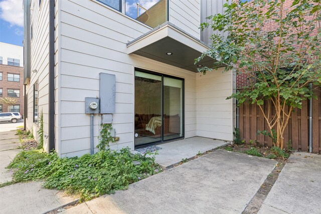 view of exterior entry featuring a patio and fence