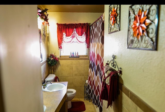 bathroom with tile patterned floors, vanity, tile walls, and toilet