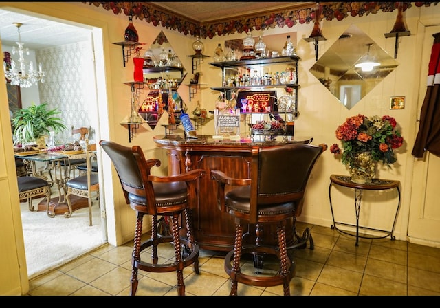 bar featuring tile patterned flooring and an inviting chandelier