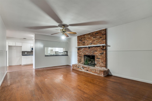 unfurnished living room with ceiling fan, hardwood / wood-style floors, and a brick fireplace