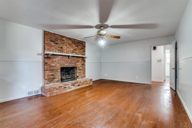 unfurnished living room featuring wood-type flooring, a brick fireplace, and ceiling fan