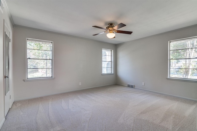 carpeted spare room with ceiling fan, crown molding, and a wealth of natural light