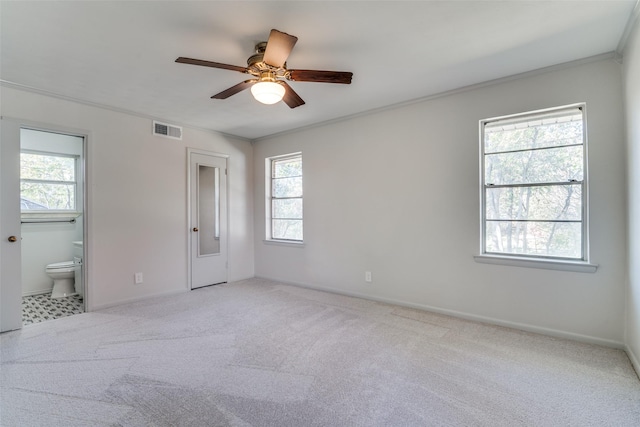 unfurnished bedroom featuring ensuite bath, ceiling fan, crown molding, and light colored carpet