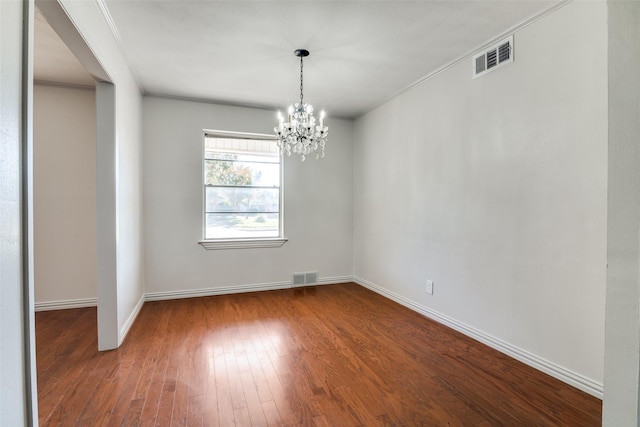 empty room featuring an inviting chandelier, ornamental molding, and hardwood / wood-style flooring