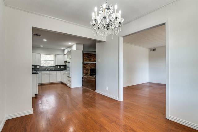 interior space featuring a chandelier, hardwood / wood-style floors, ornamental molding, and sink