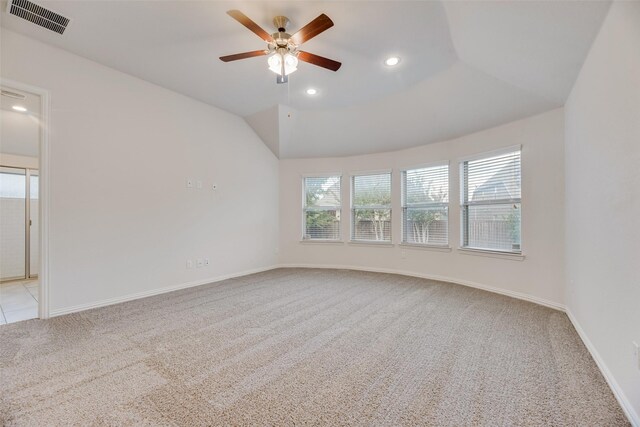 empty room featuring lofted ceiling, light colored carpet, ceiling fan, and a healthy amount of sunlight