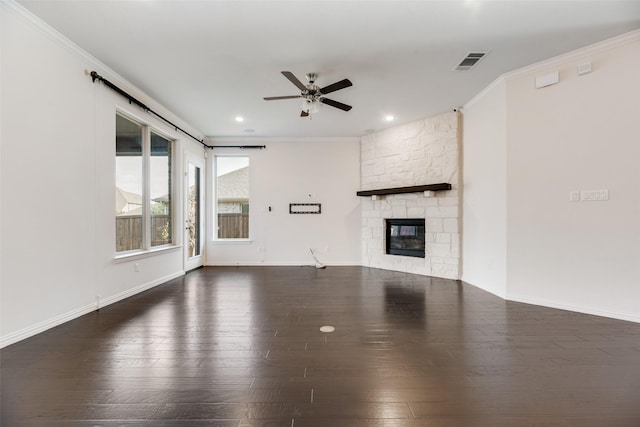 unfurnished living room with dark hardwood / wood-style floors, a stone fireplace, ceiling fan, and crown molding