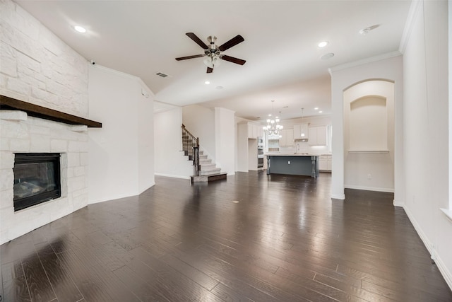 unfurnished living room with a fireplace, crown molding, dark wood-type flooring, and ceiling fan with notable chandelier