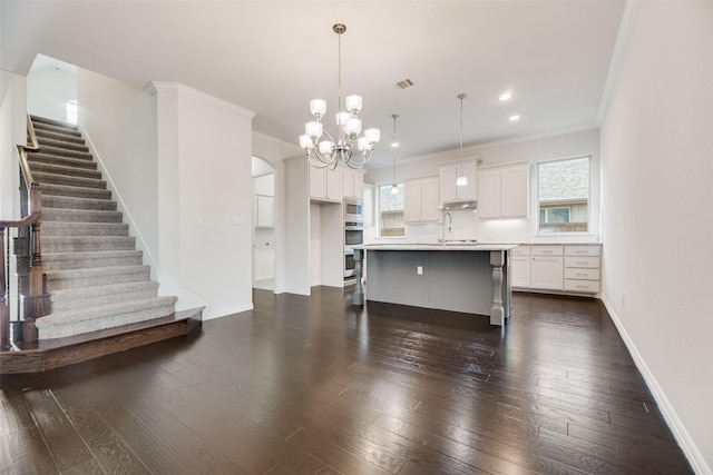 kitchen with plenty of natural light, dark hardwood / wood-style flooring, a kitchen island with sink, and decorative light fixtures