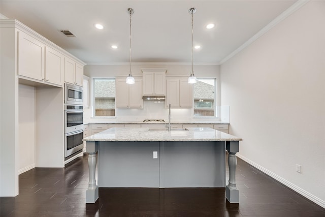 kitchen featuring pendant lighting, white cabinets, a center island with sink, light stone countertops, and appliances with stainless steel finishes