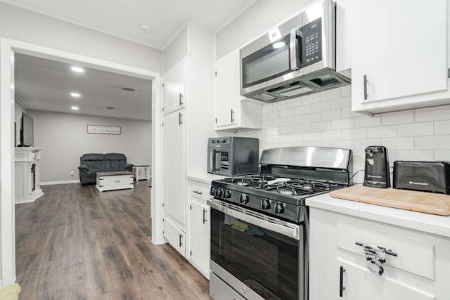 kitchen featuring tasteful backsplash, white cabinetry, stainless steel appliances, and dark wood-type flooring