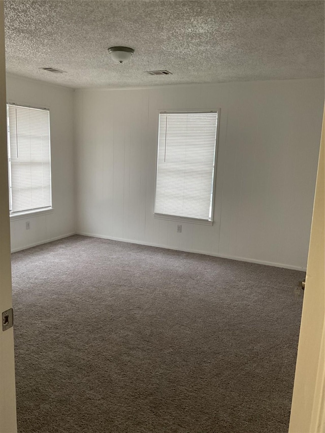 empty room featuring dark carpet and a textured ceiling