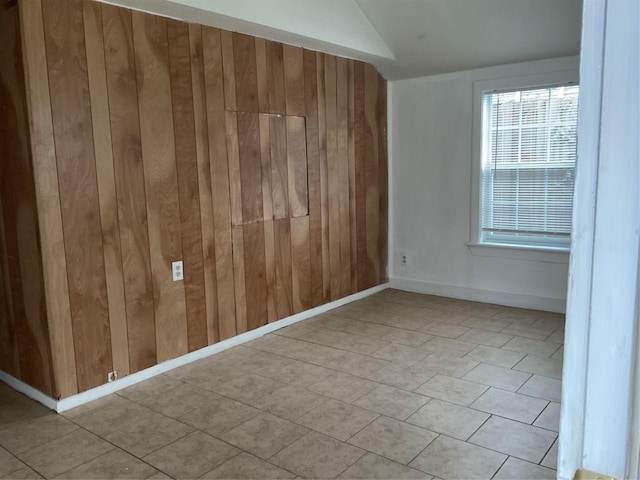 unfurnished room featuring lofted ceiling and wood walls