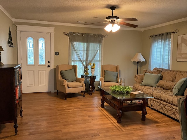 living room with crown molding, ceiling fan, a textured ceiling, and light wood-type flooring