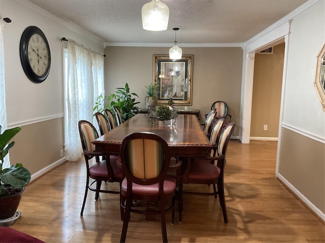 dining space with hardwood / wood-style floors, ornamental molding, and a textured ceiling