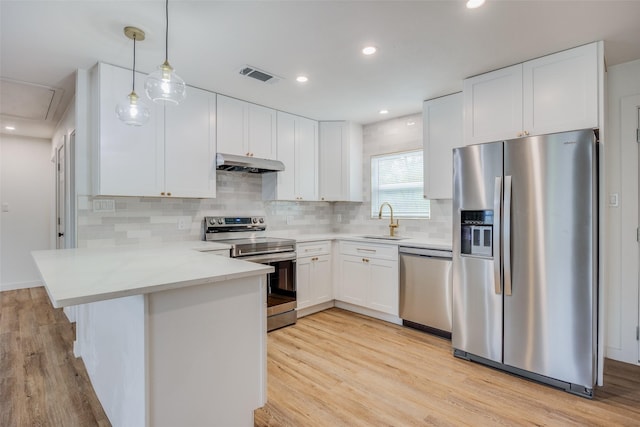 kitchen with kitchen peninsula, appliances with stainless steel finishes, white cabinetry, and light hardwood / wood-style flooring