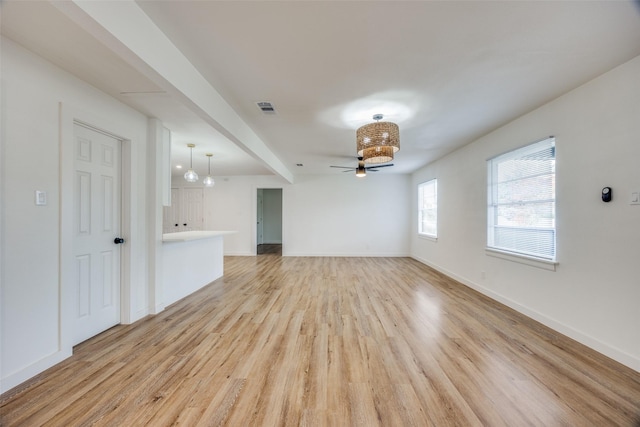 unfurnished living room with ceiling fan, beamed ceiling, and light hardwood / wood-style floors